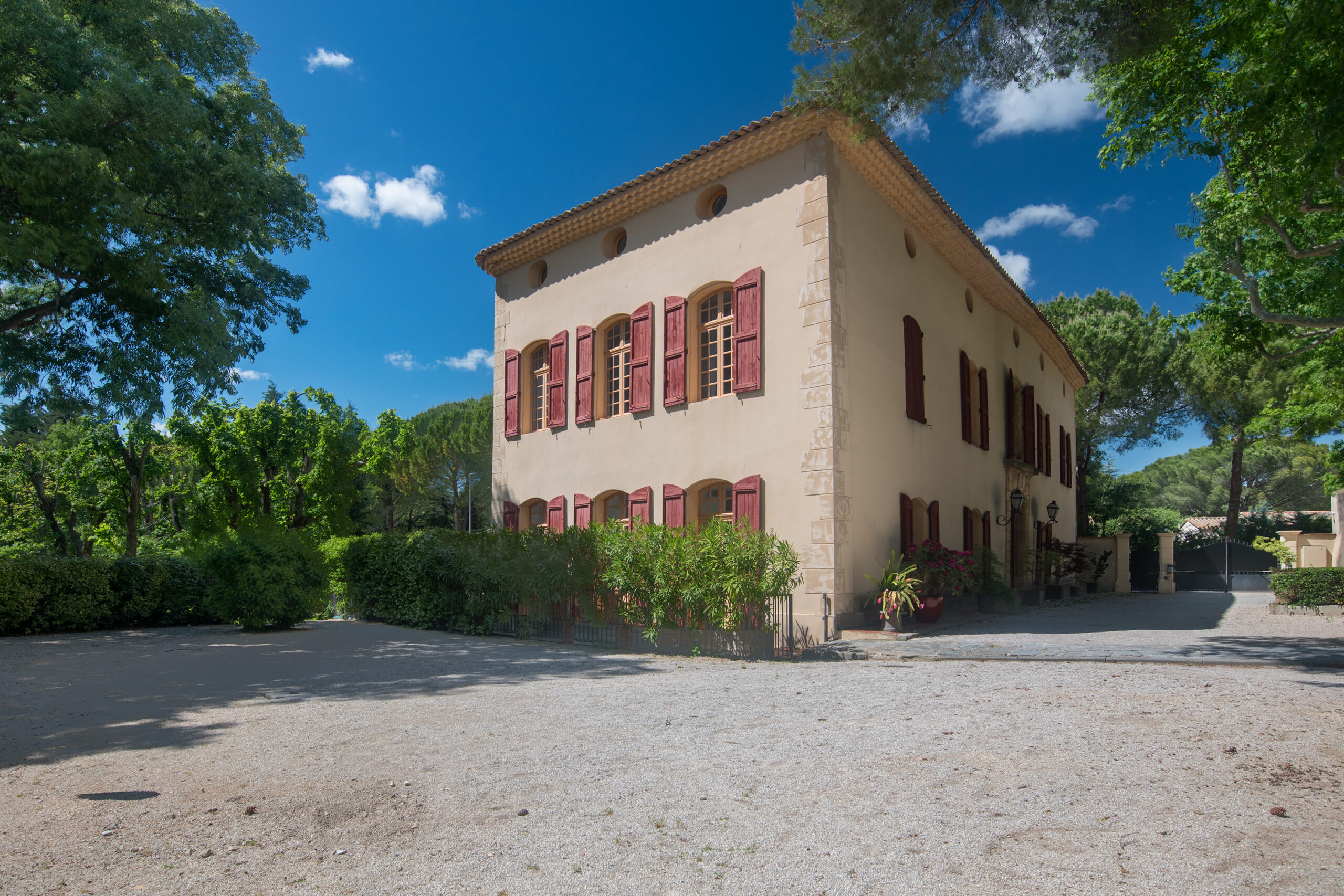 a building with red shutters and a gravel driveway