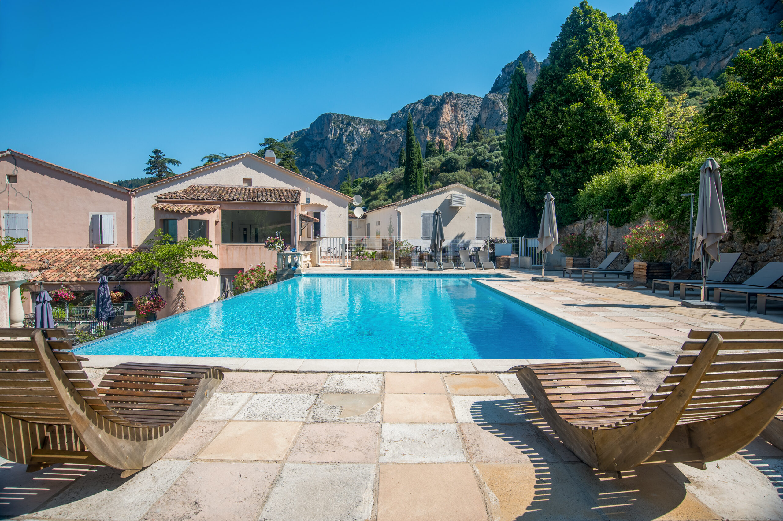 deux chaises longues; piscine et deux maisons à l'arrière